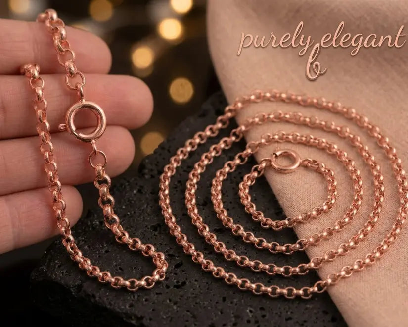Rose gold chain necklace on a textured surface with 'purely elegant' branding.