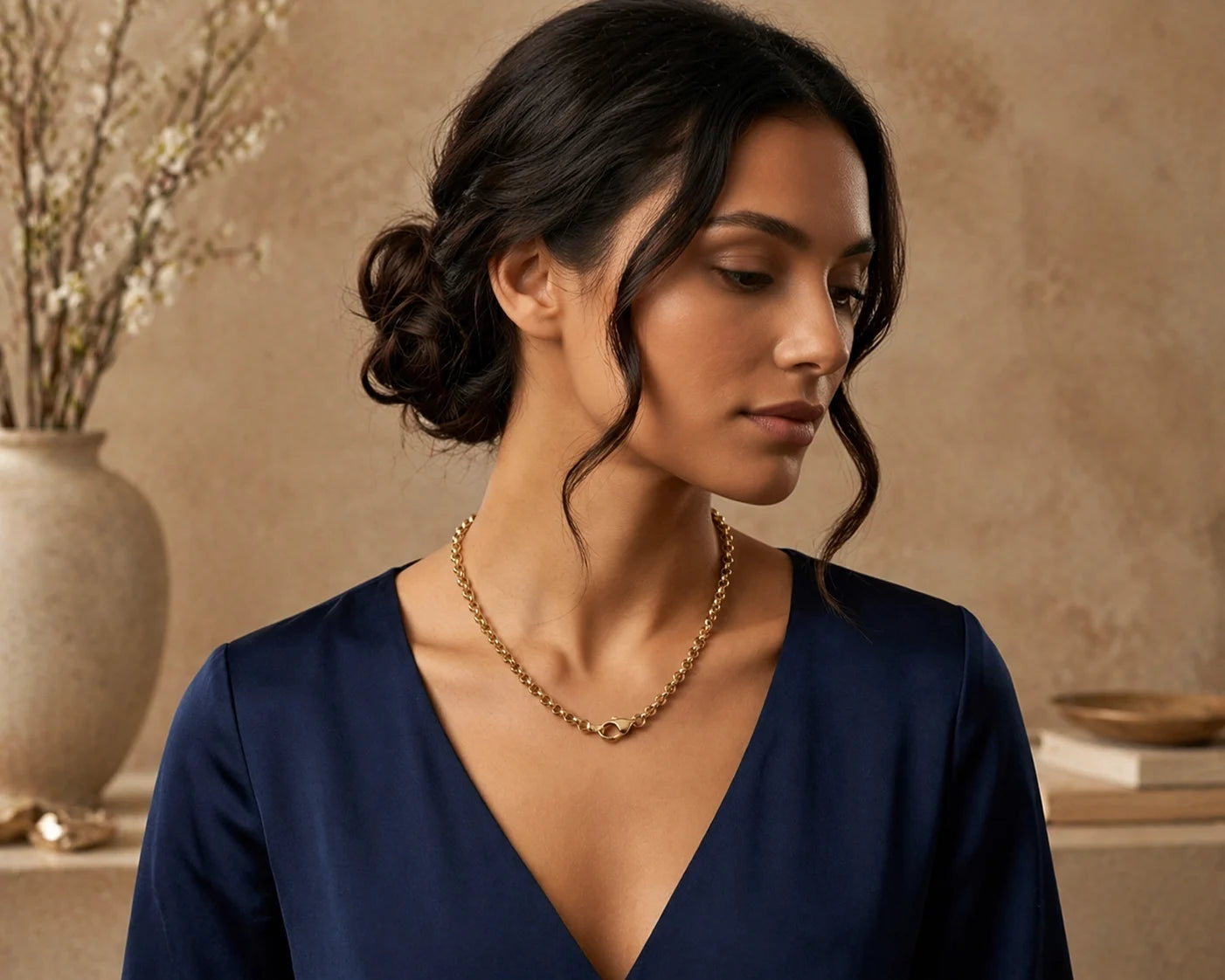 Woman wearing a gold necklace with a neutral background