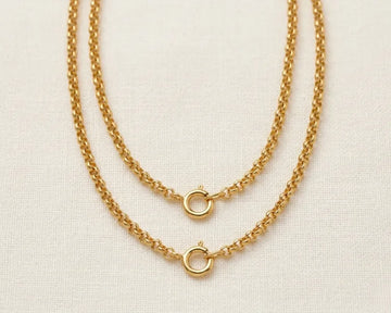 Two gold chain necklaces on a light beige background