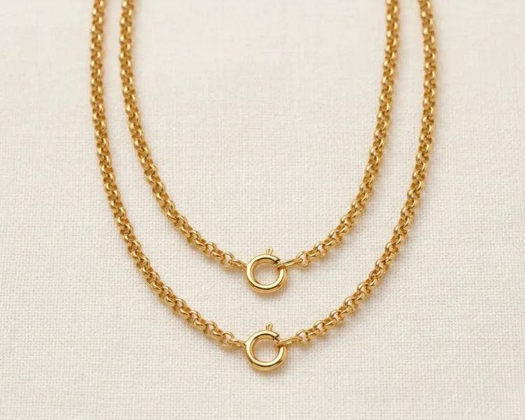 Two gold chain necklaces on a light beige background
