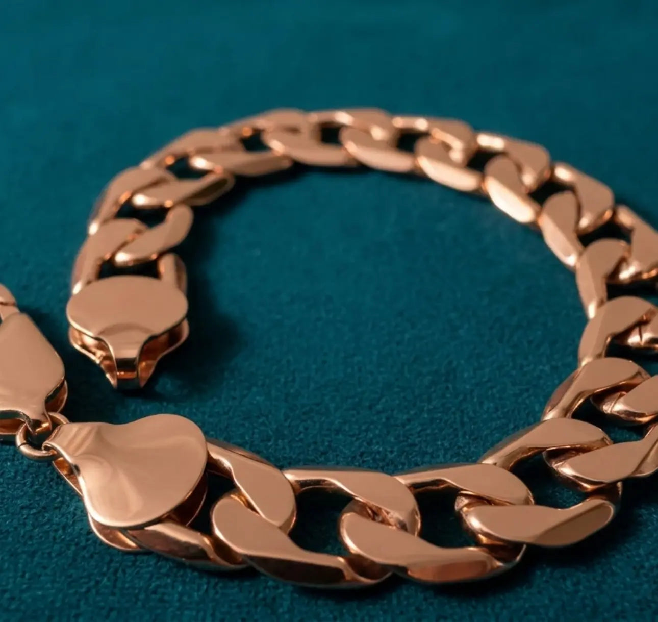 Rose gold chain bracelet on a blue textured background