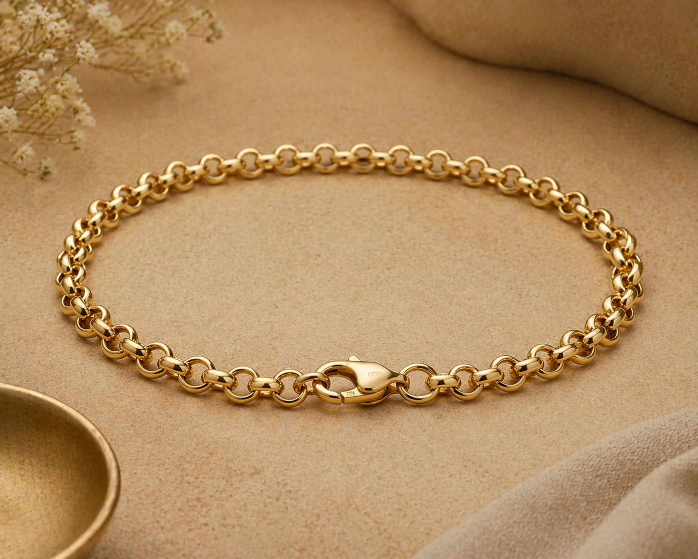 Gold chain bracelet on a beige surface with a soft focus background