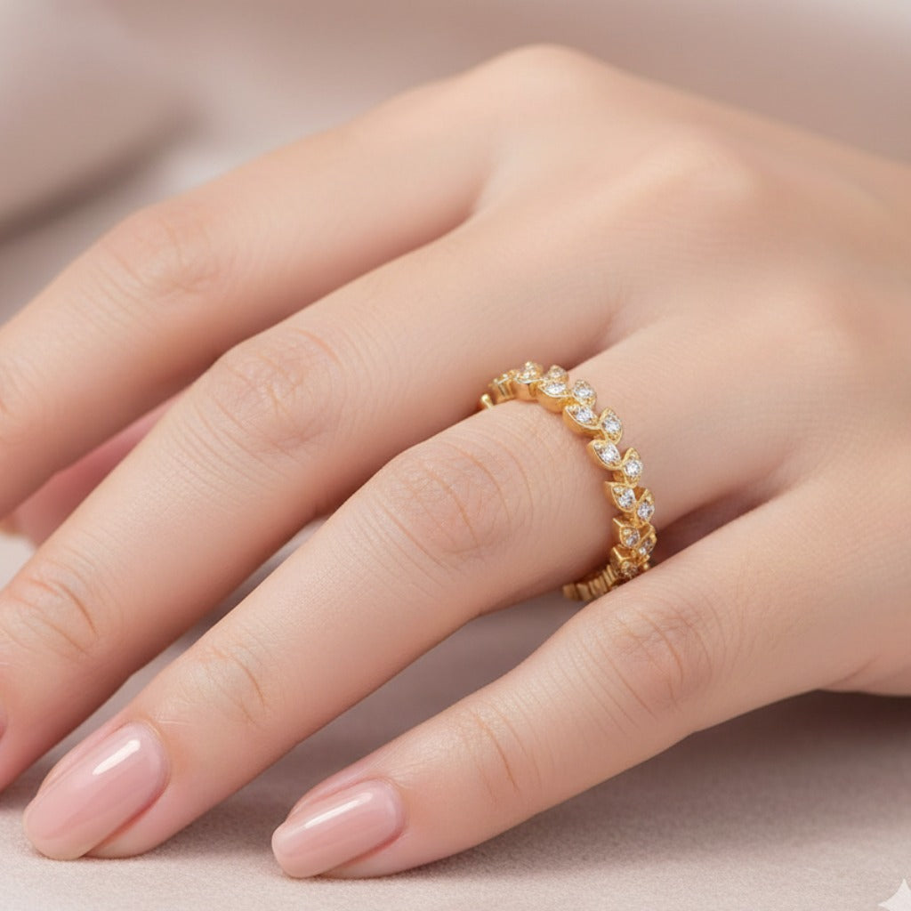 Gold ring with diamonds on a finger against a neutral background
