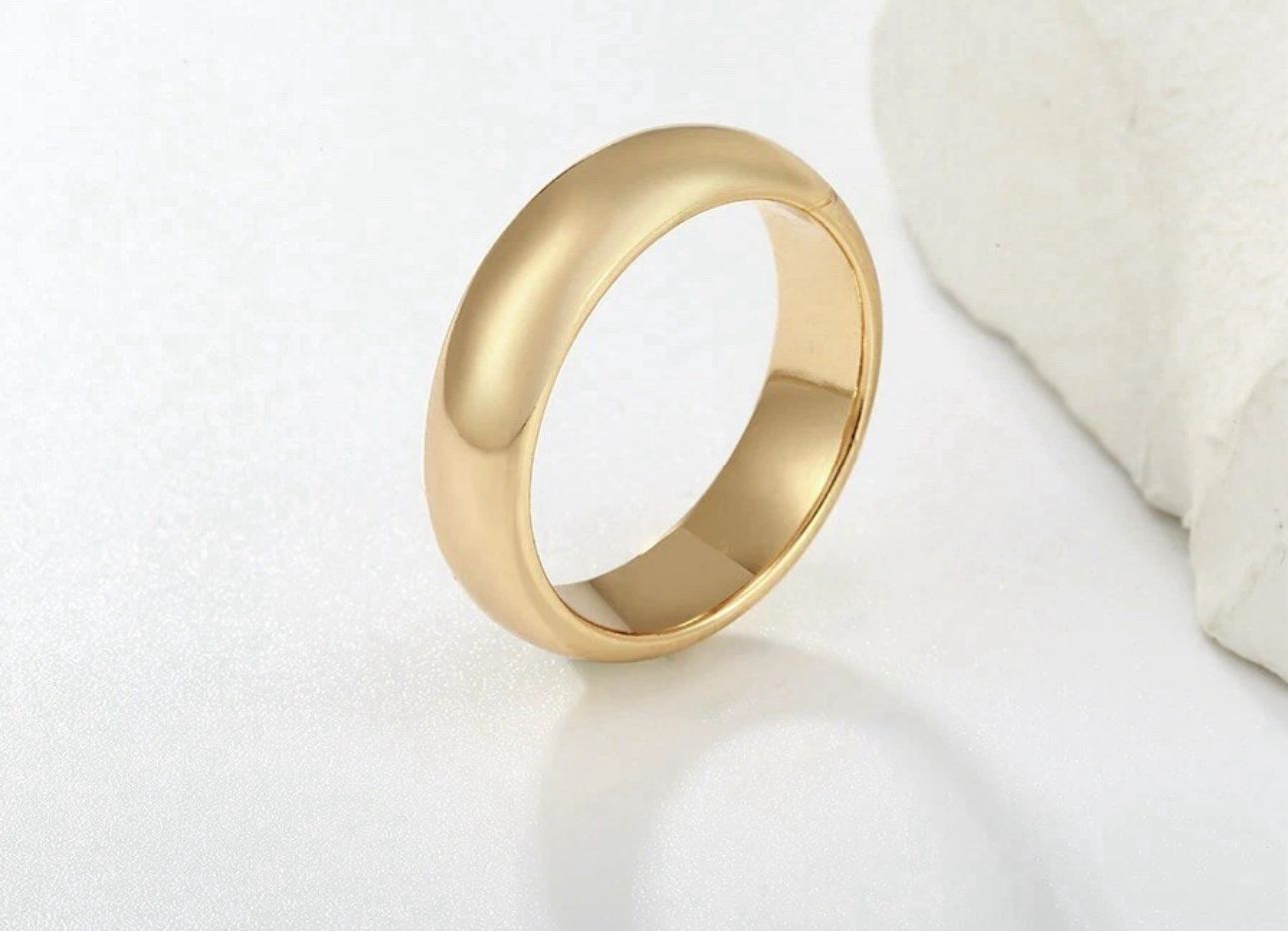 Gold ring on a white surface with a neutral background