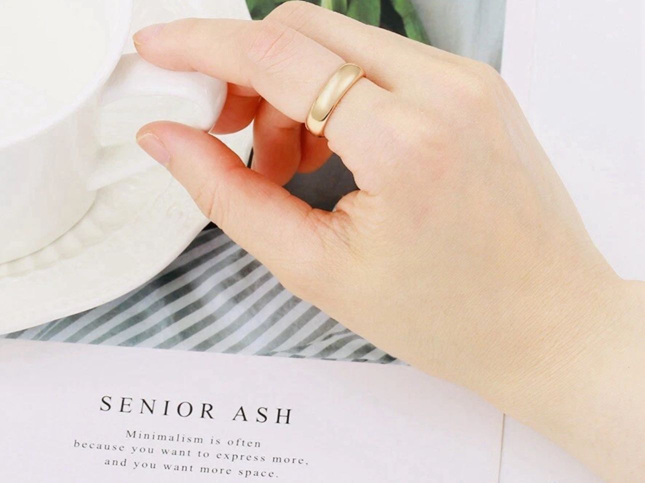 Hand wearing a gold ring on a white background with text overlayshop_this_look_AVdw3f