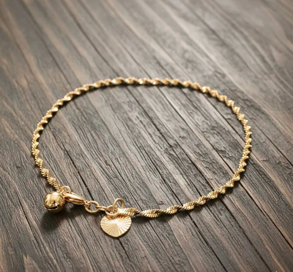 Gold bracelet with a small charm on a wooden surface