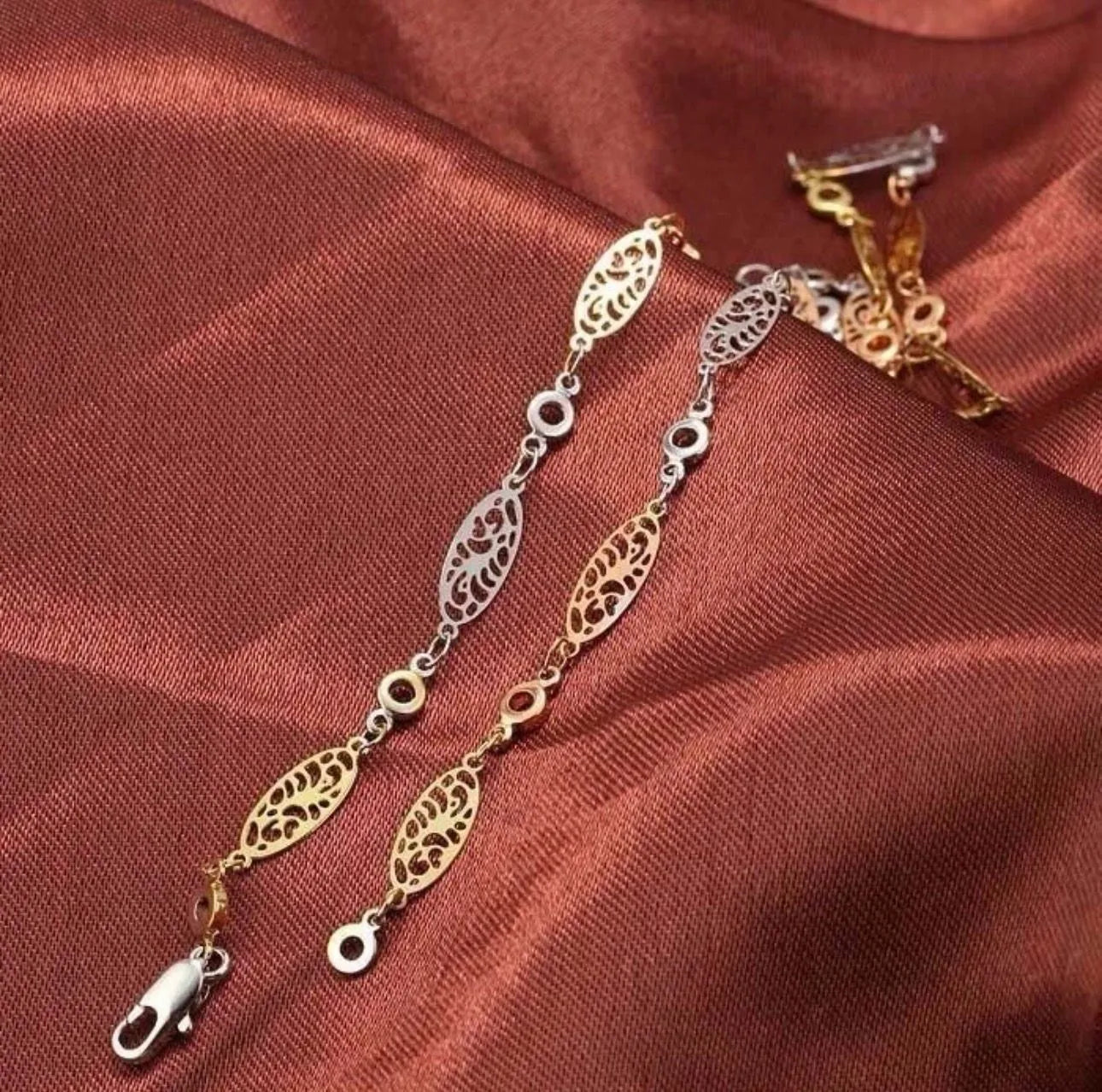 Gold and silver chain with clasp on a red fabric background