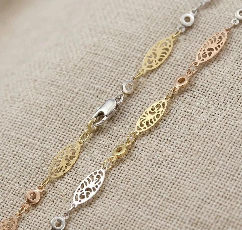 Gold bracelet with intricate designs on a beige fabric background