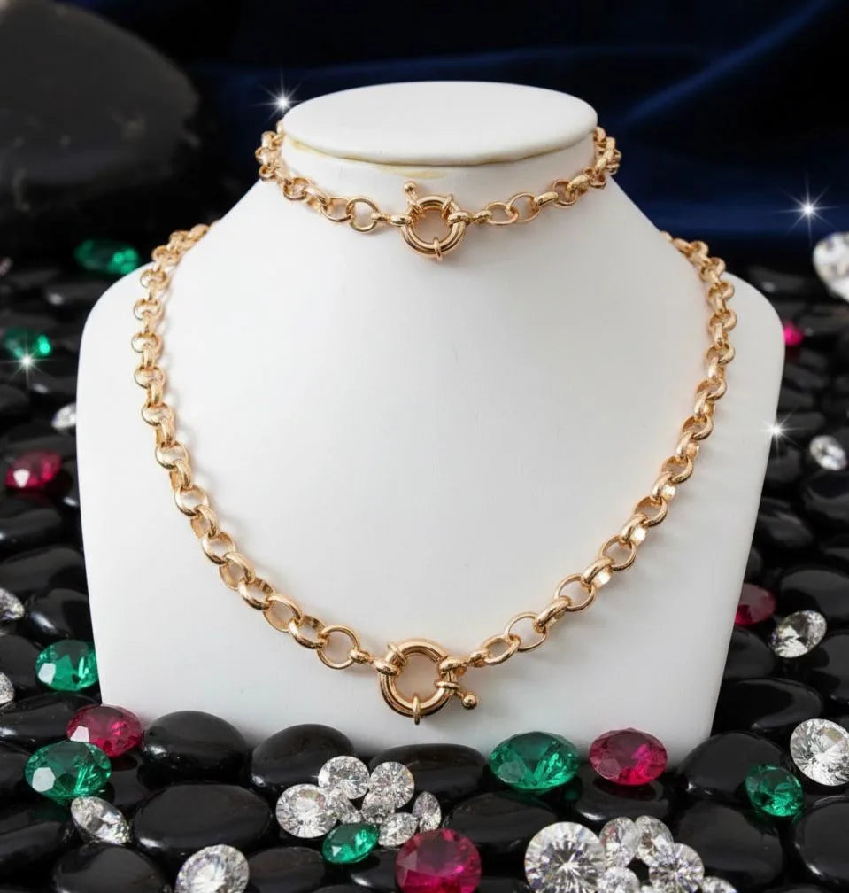 Gold chain necklace on a white mannequin bust with colorful gemstones below.