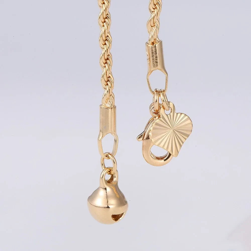 Gold necklace with heart and bell pendants on a light gray background