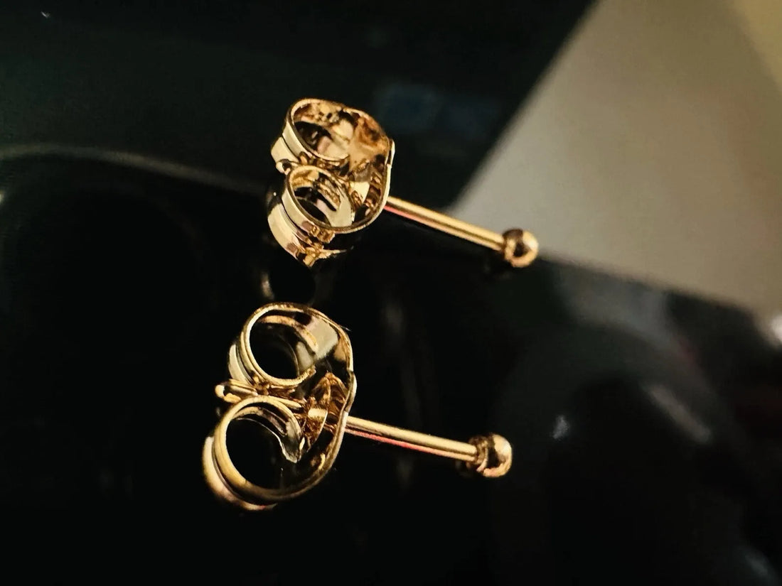 Gold earrings on a white surface