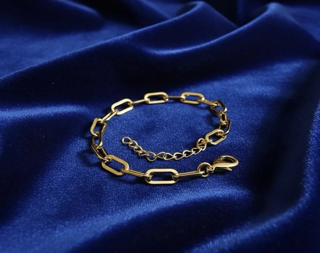 Gold chain bracelet on a blue satin background