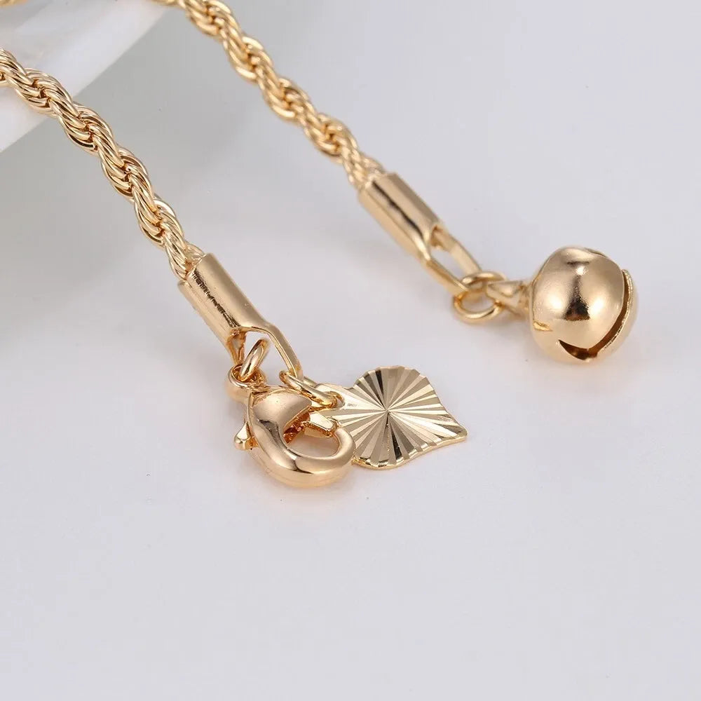 Gold necklace with heart and leaf charms on a light gray background