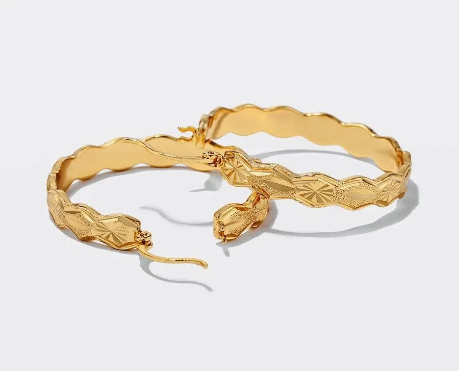 Two gold bangles on a light gray background