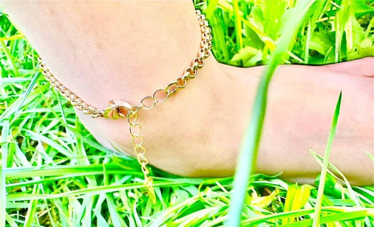 Gold anklet on a foot with grass in the background
