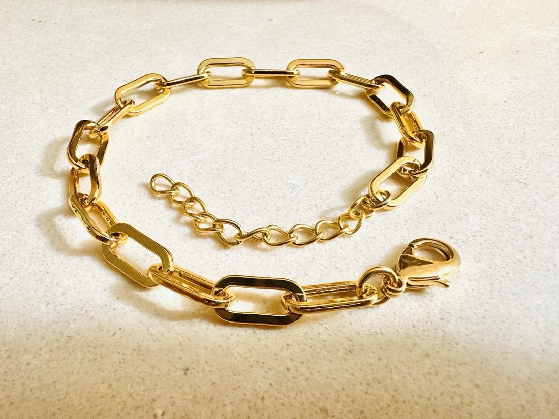 Gold chain bracelet on a wrist with a dark background