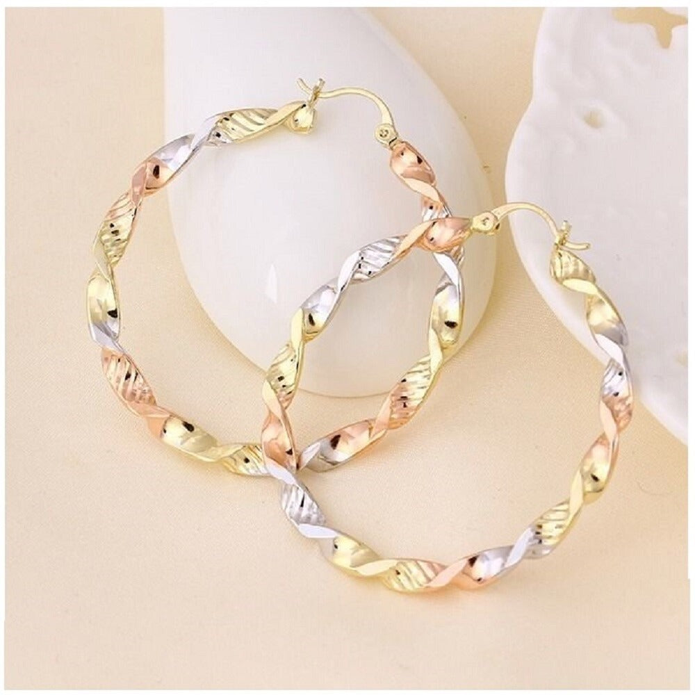 Tri-color gold hoop earrings on a light beige background