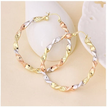 Tri-color gold hoop earrings on a light beige background