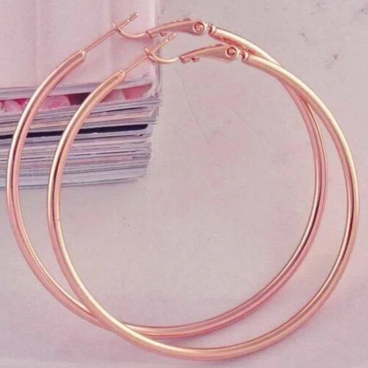 Rose gold hoop earrings on a light pink background
