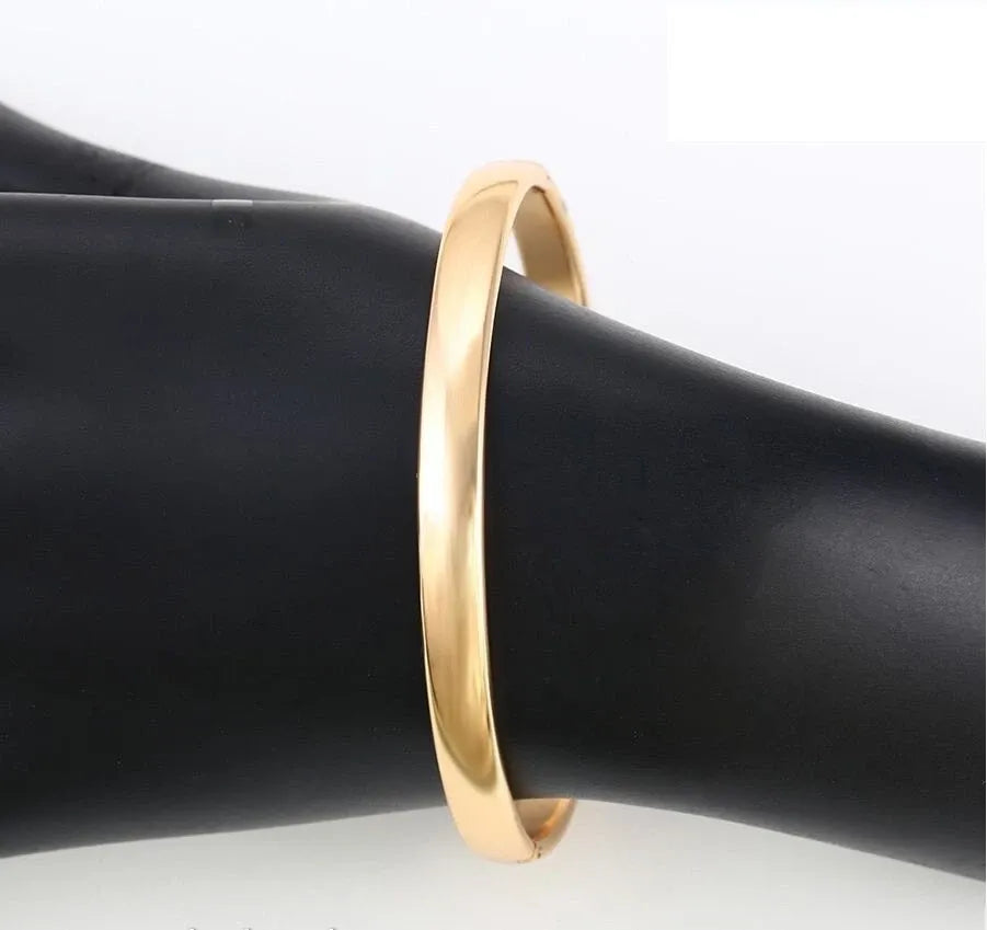 Gold bracelet on a black mannequin arm against a white background