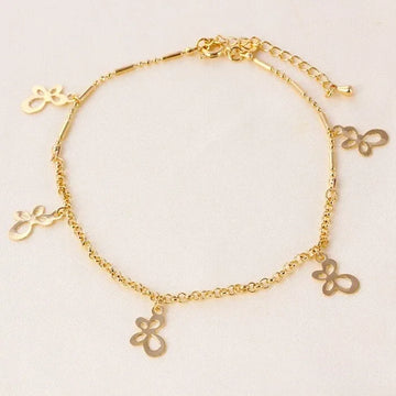 Gold anklet with butterfly charms on a light beige background