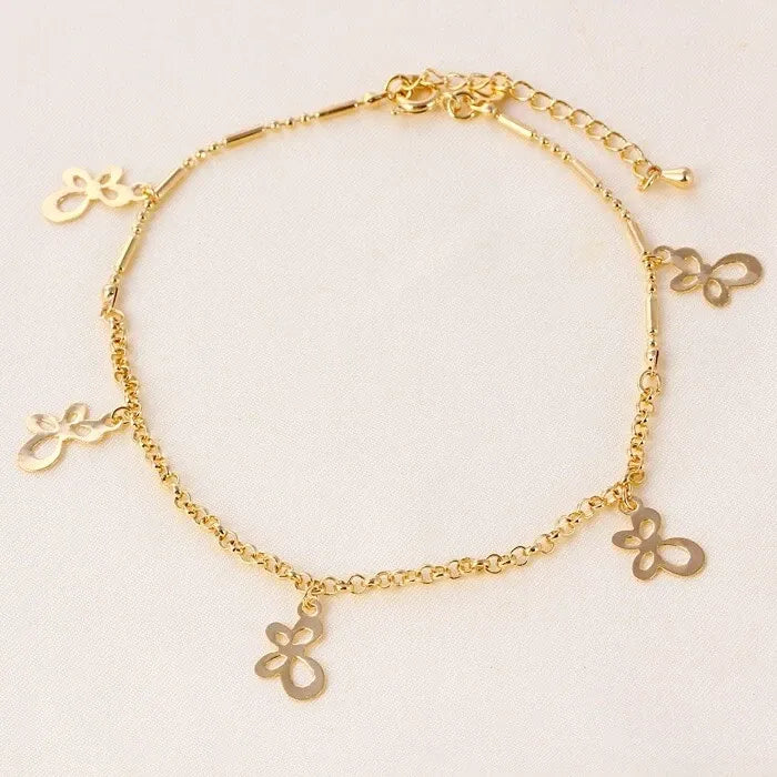 Gold anklet with butterfly charms on a light beige background
