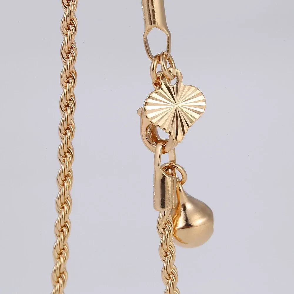 Gold necklace with heart and teardrop pendants on a light gray background