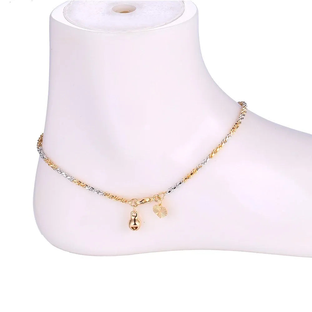Gold anklet on a mannequin foot against a white background