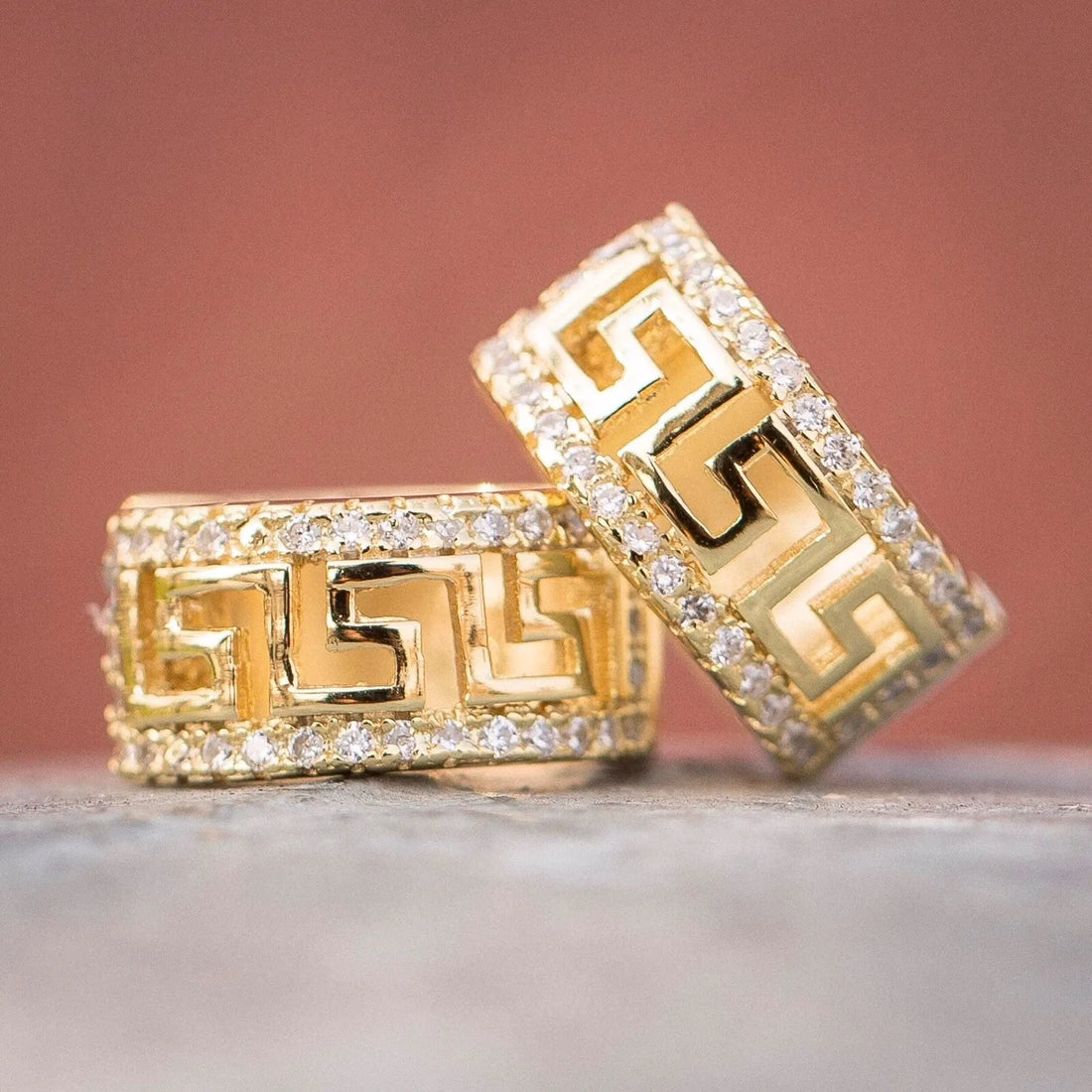 Gold rings with intricate designs on a neutral background
