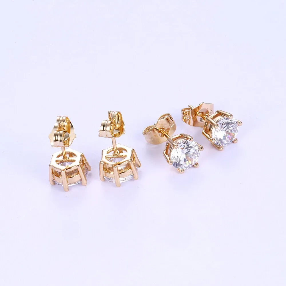 Gold stud earrings with clear gemstones on a light purple background