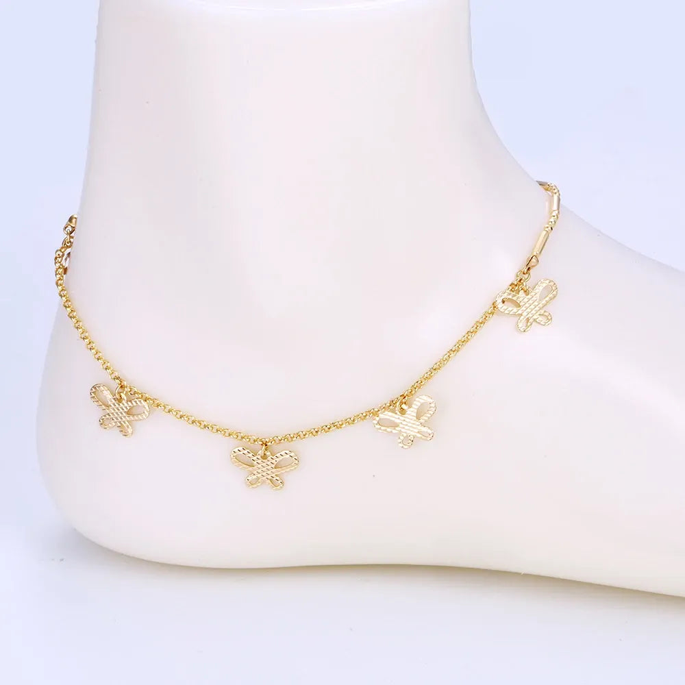 Gold butterfly anklet on a white mannequin foot against a light purple background