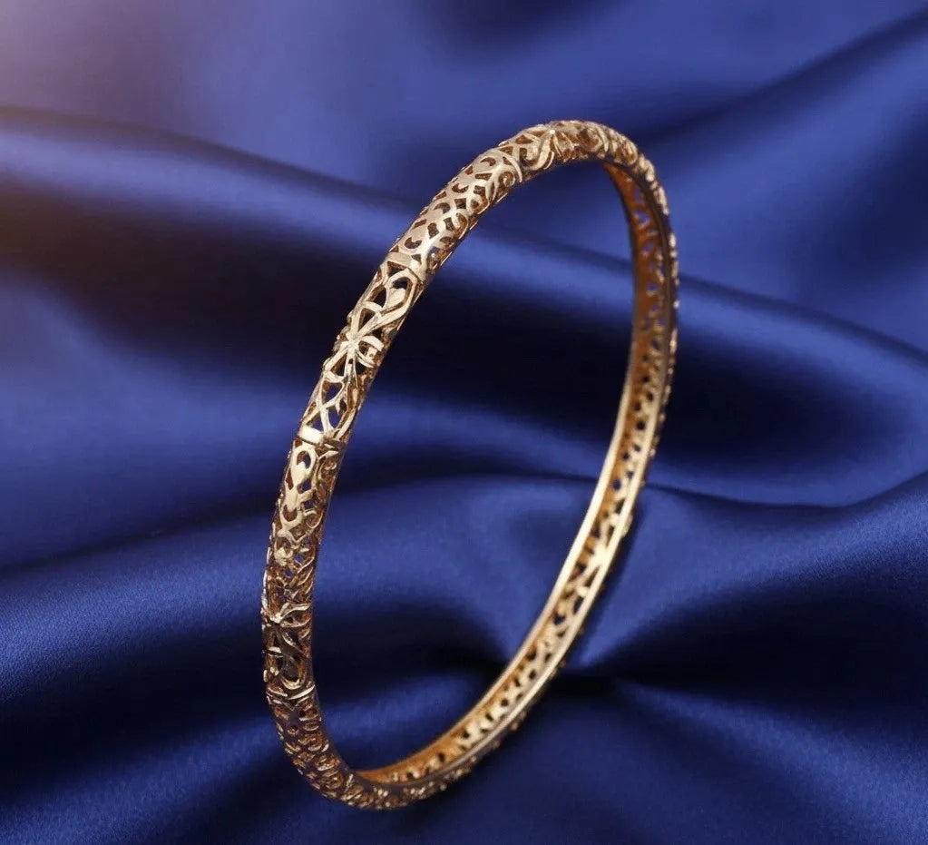 Gold bracelet with intricate design on a blue fabric background