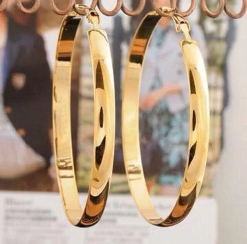 Gold hoop earrings on a blurred background