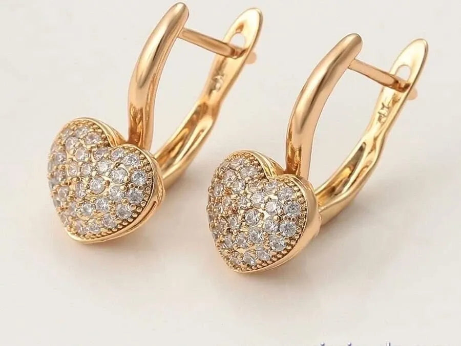Gold heart-shaped earrings with diamond accents on a light background