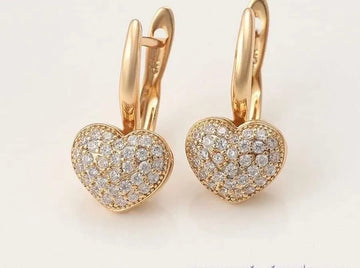 Heart-shaped gold earrings with diamond accents on a light background