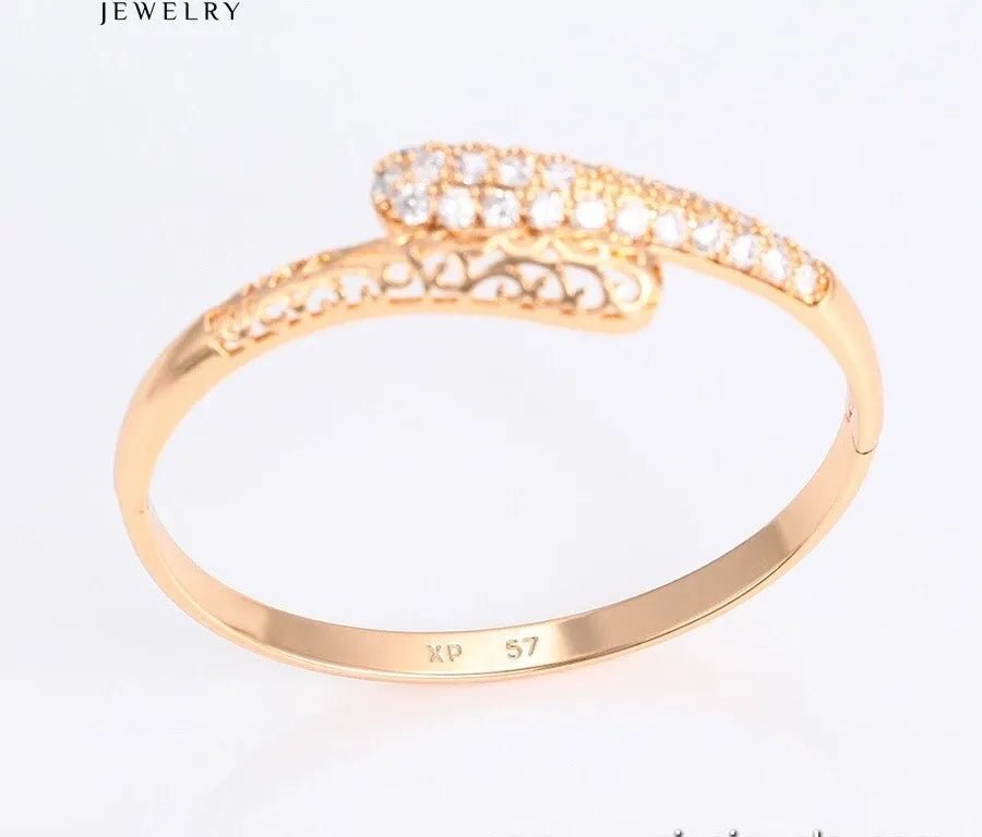 gold open bangle with intricate design on a white background