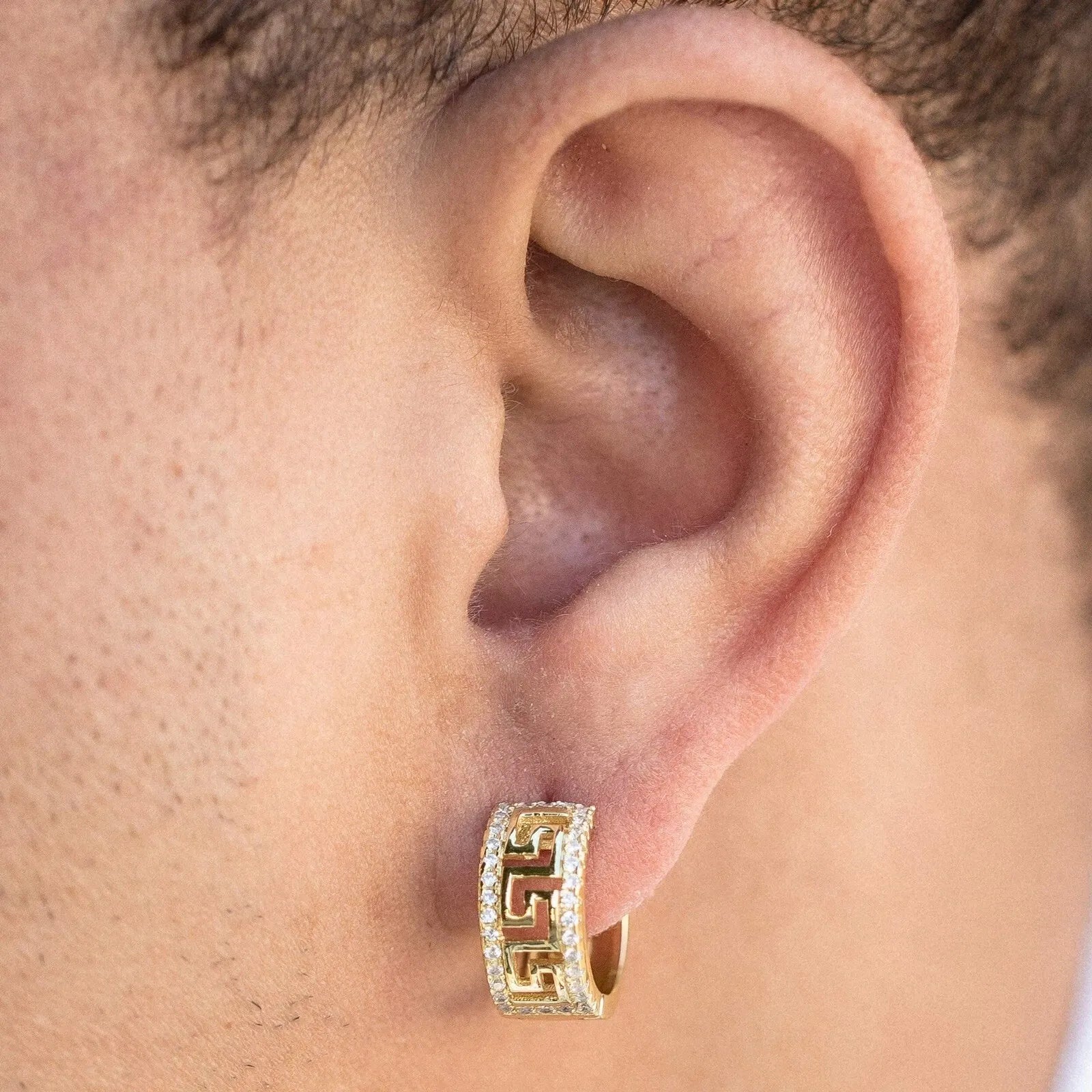 Gold hoop earring worn on a person's ear