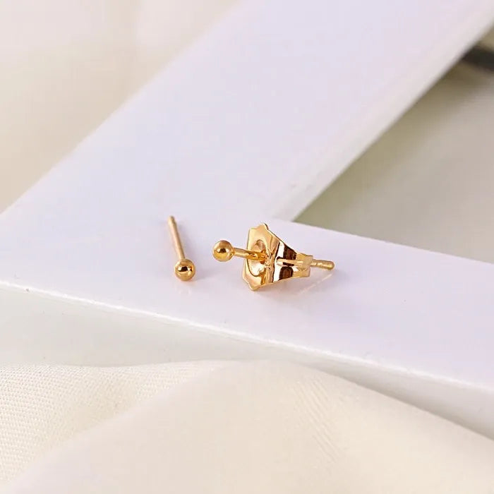 Gold earrings on a white surface