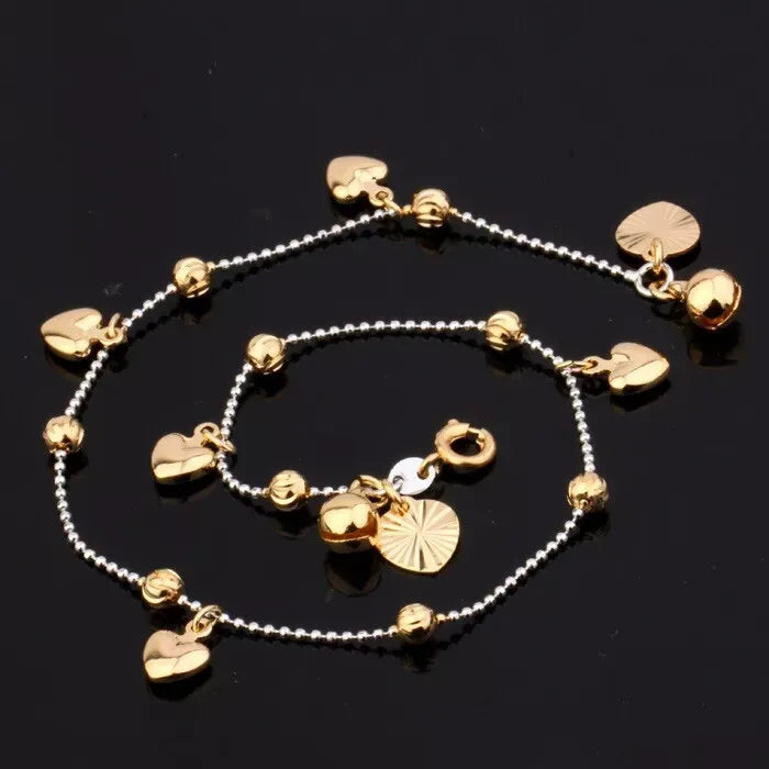 Gold anklets with heart-shaped charms on a black background