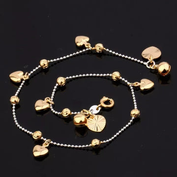 Gold anklets with heart-shaped charms on a black background