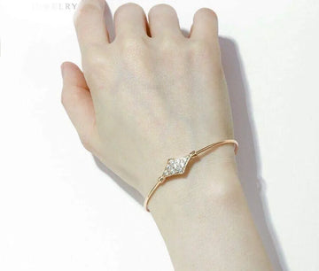  gold bracelet with clear stones on a wrist against a white background