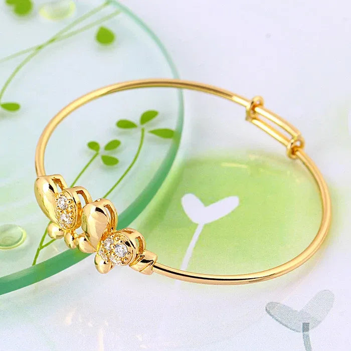 Gold bracelet with butterfly design on a light green background