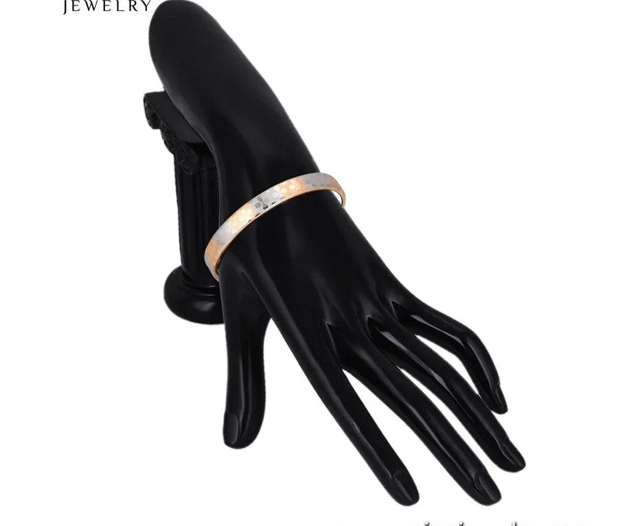 Black mannequin hand holding a gold ring with 'Jewelry' text above
