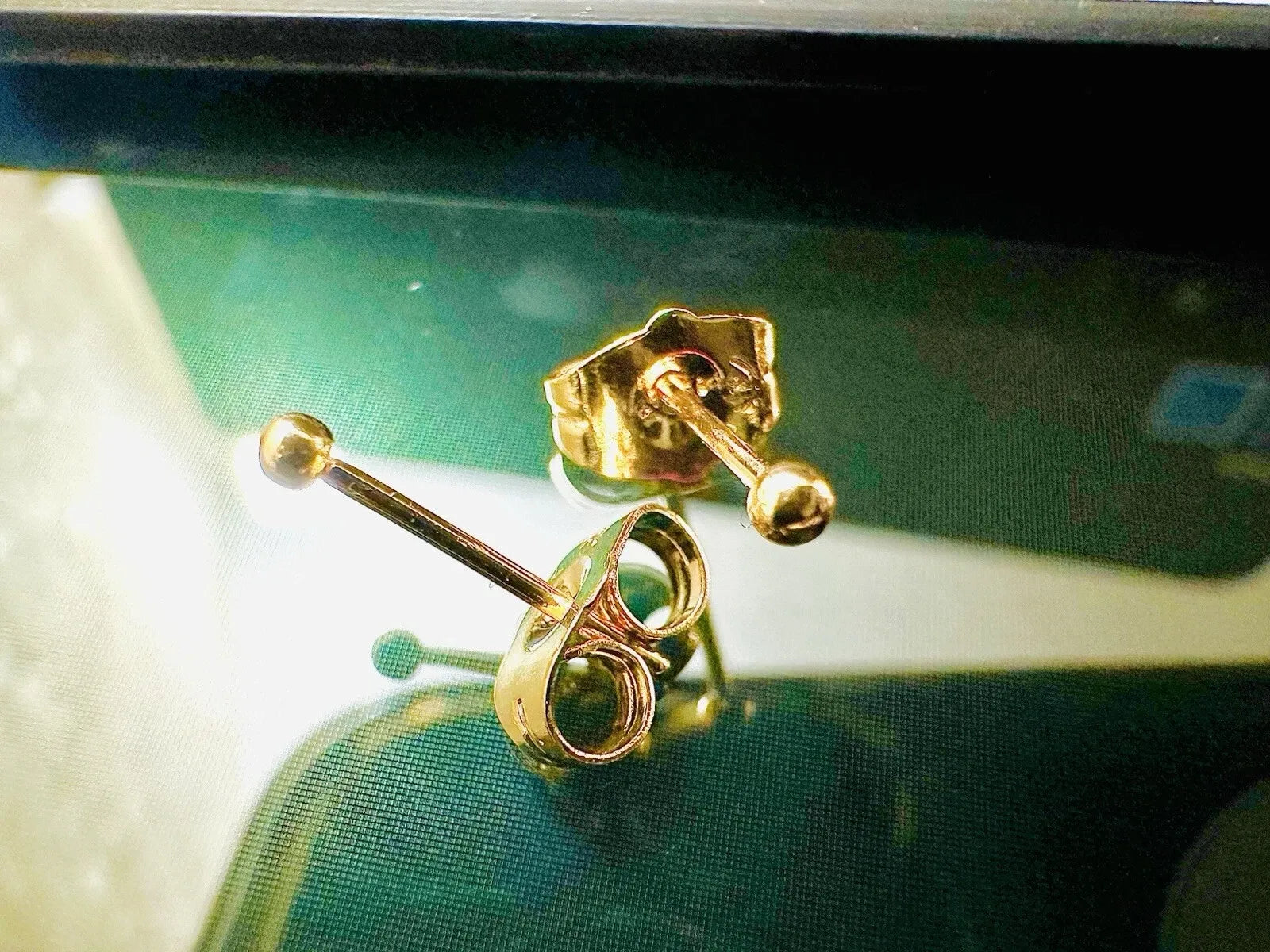 Gold earrings on a reflective surface