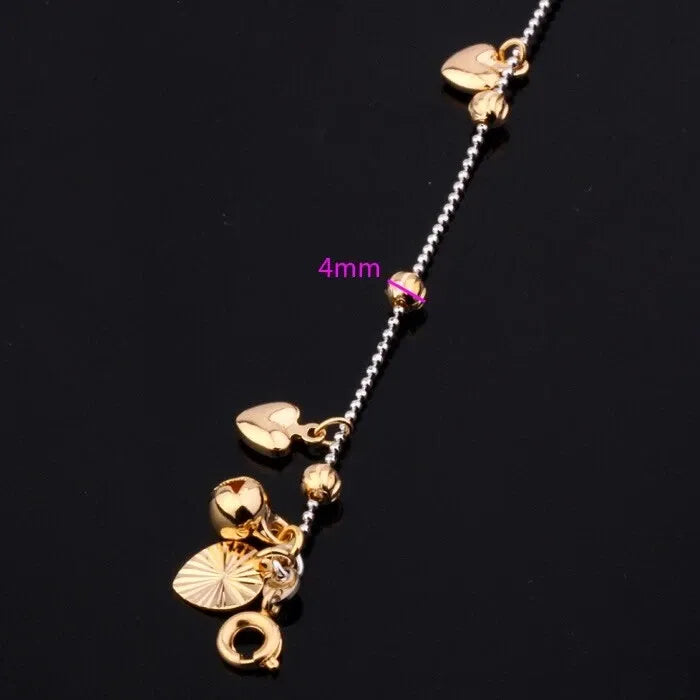 Gold anklet with heart-shaped pendants on a black background