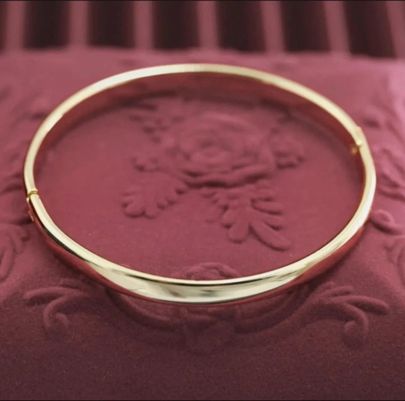 Gold bracelet on a textured red surface