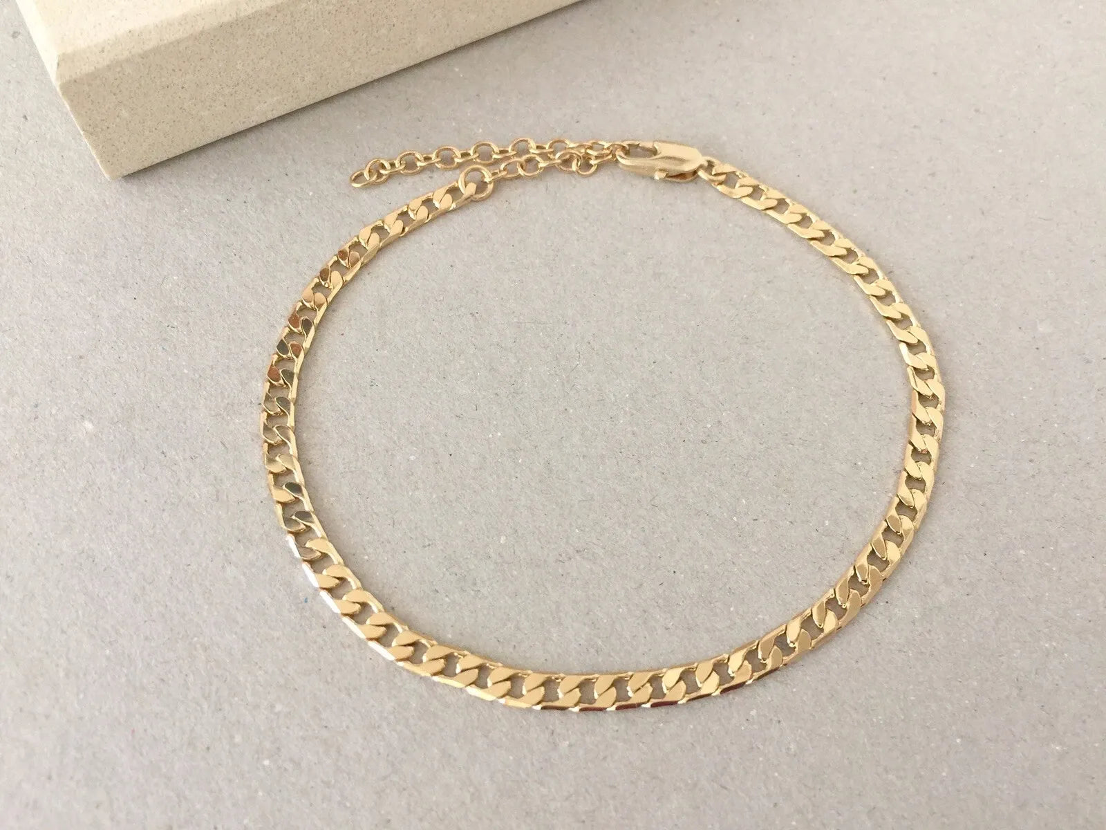 Gold chain Anklets on a light gray surface