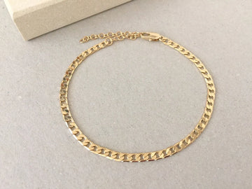 Gold chain Anklets on a light gray surface