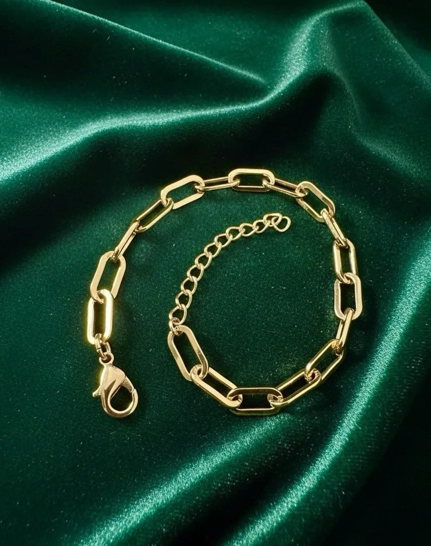 Gold chain bracelet on a green satin background