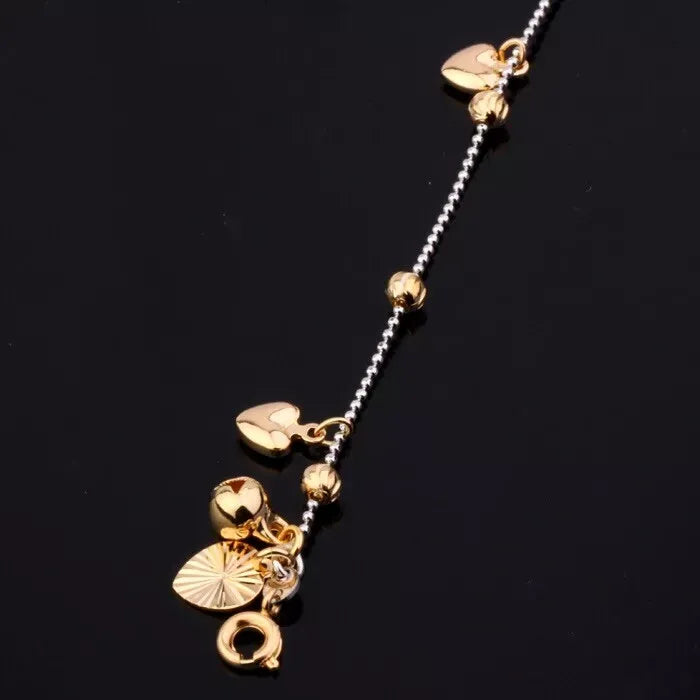 Gold anklet with heart-shaped pendants on a black background